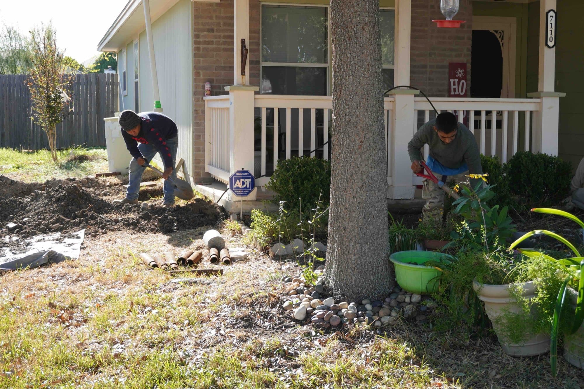 Above All Foundation Repair crew members digging pier holes at the front of a home