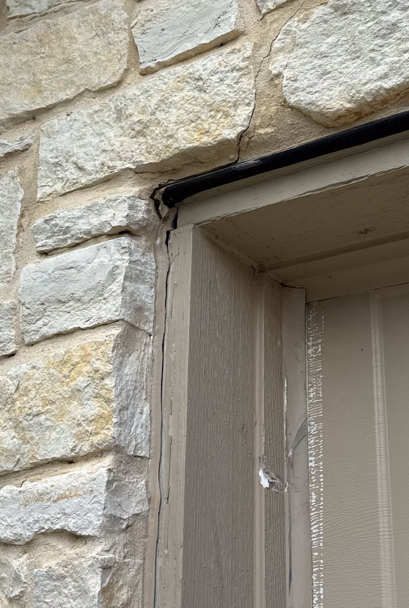 Diagonal crack in stone masonry above a garage door corner