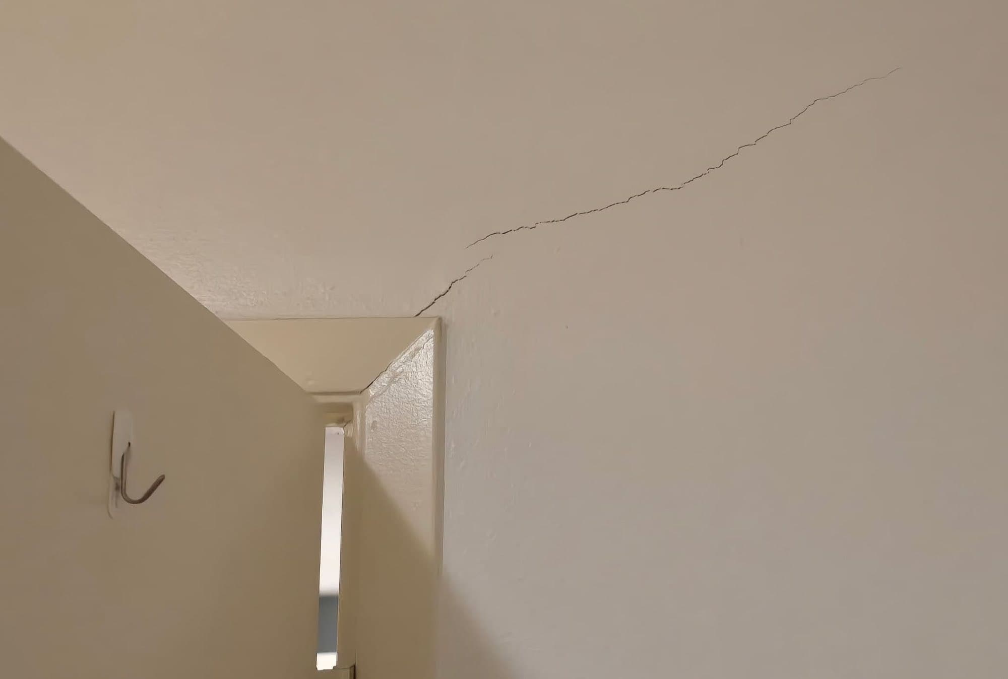 A crack running across a ceiling from a wall corner inside a home