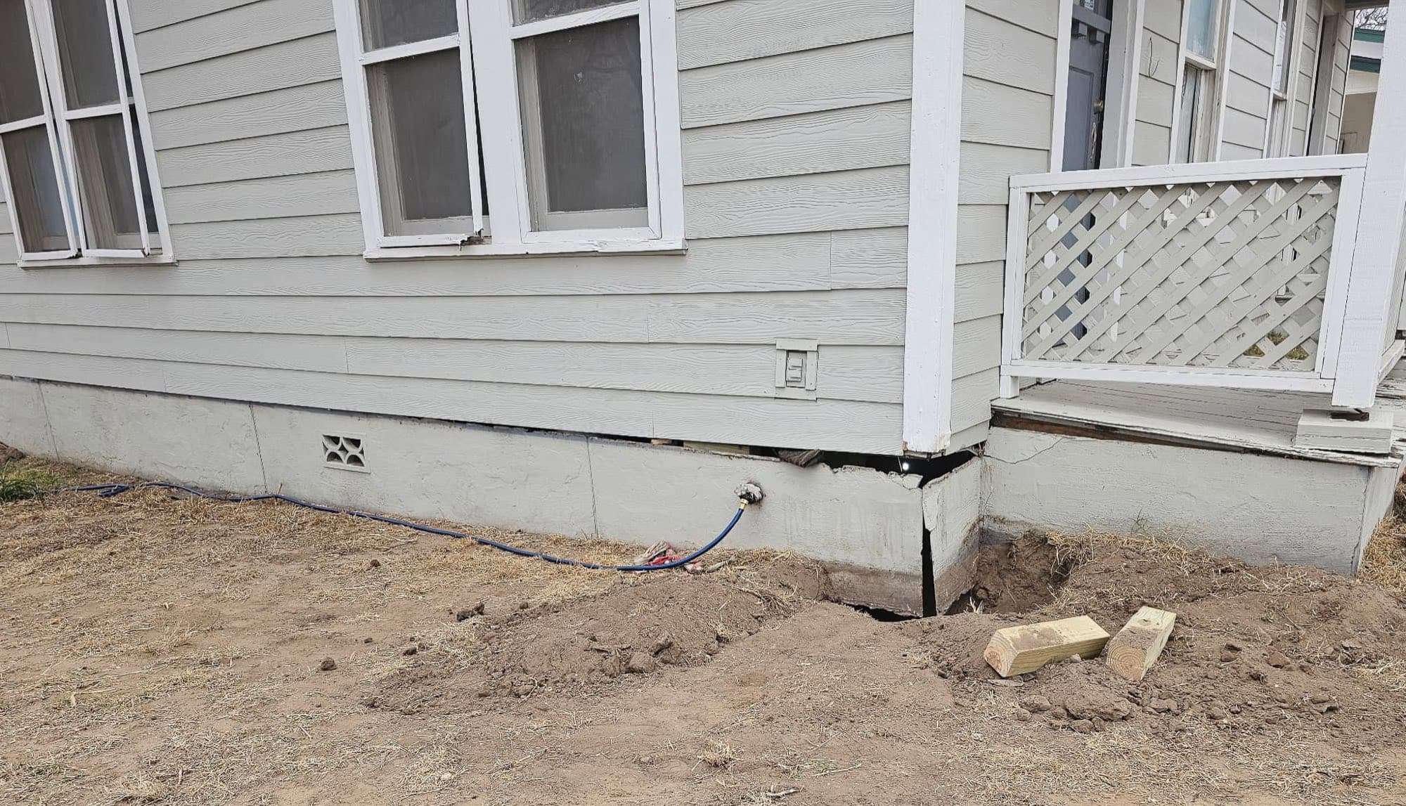 A home's corner with a separated, failing perimeter foundation exposed during repair