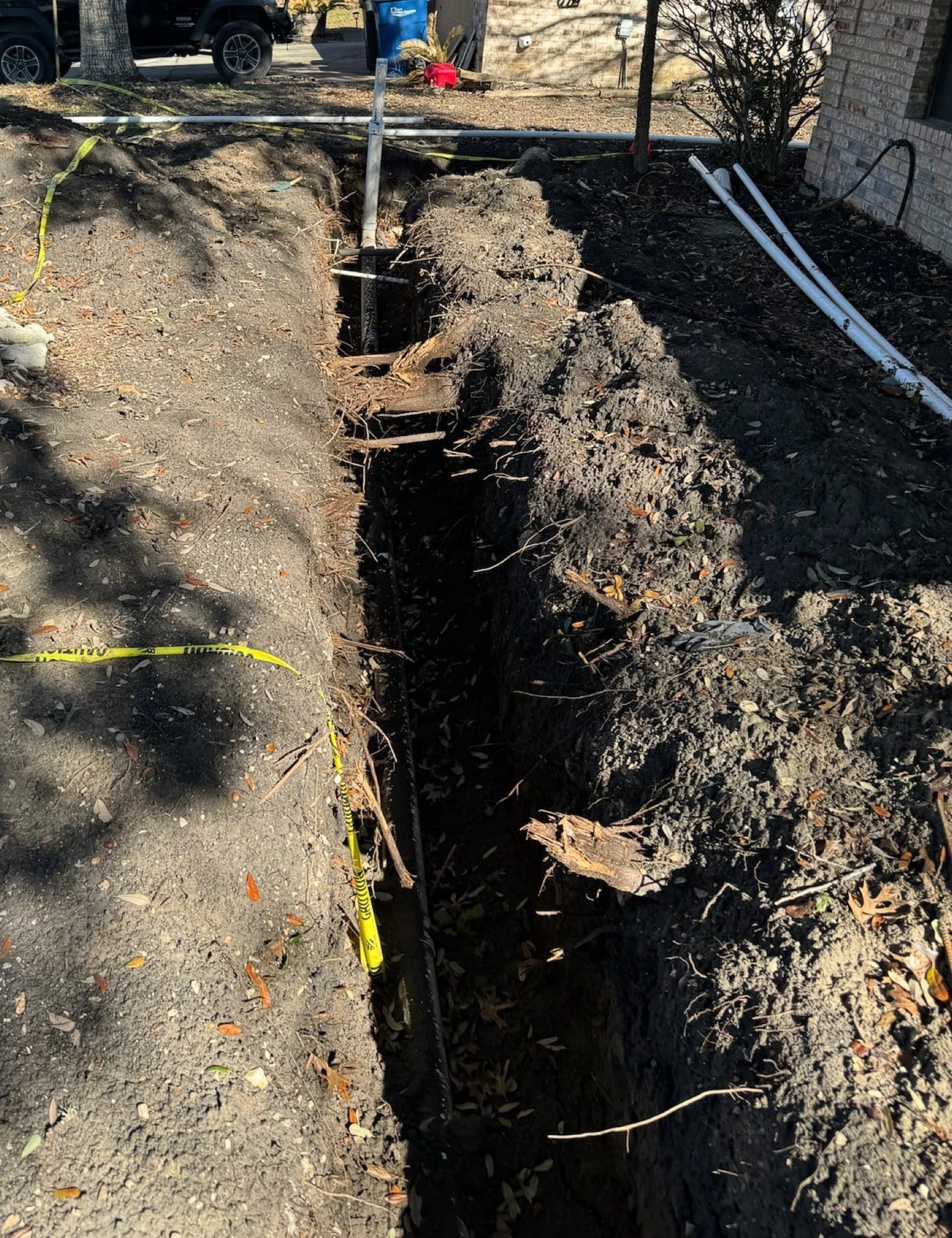 A trench excavated along a home exposing plumbing lines during under-slab repairs
