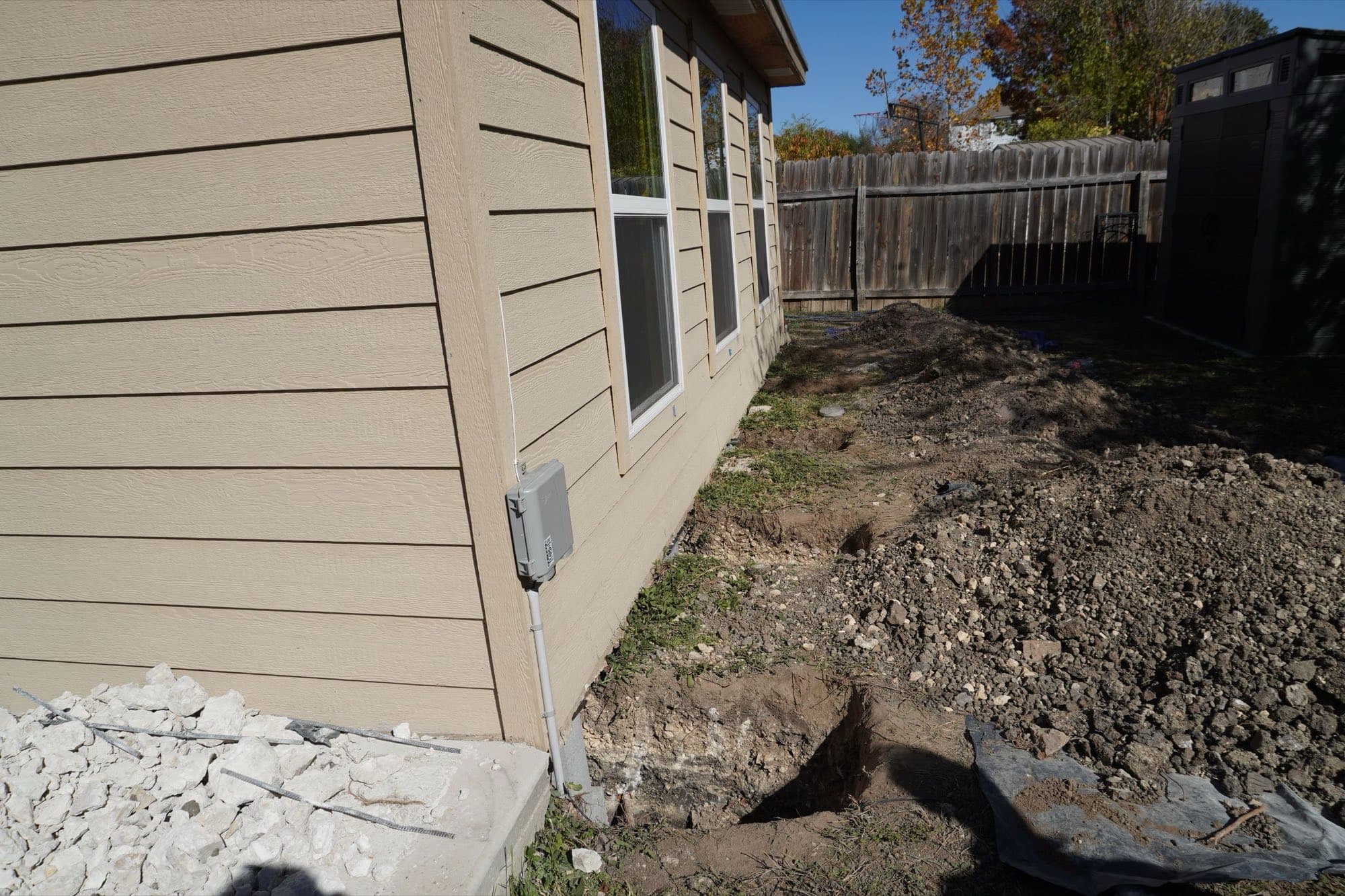 Holes dug around a slab, exposing the soil beneath