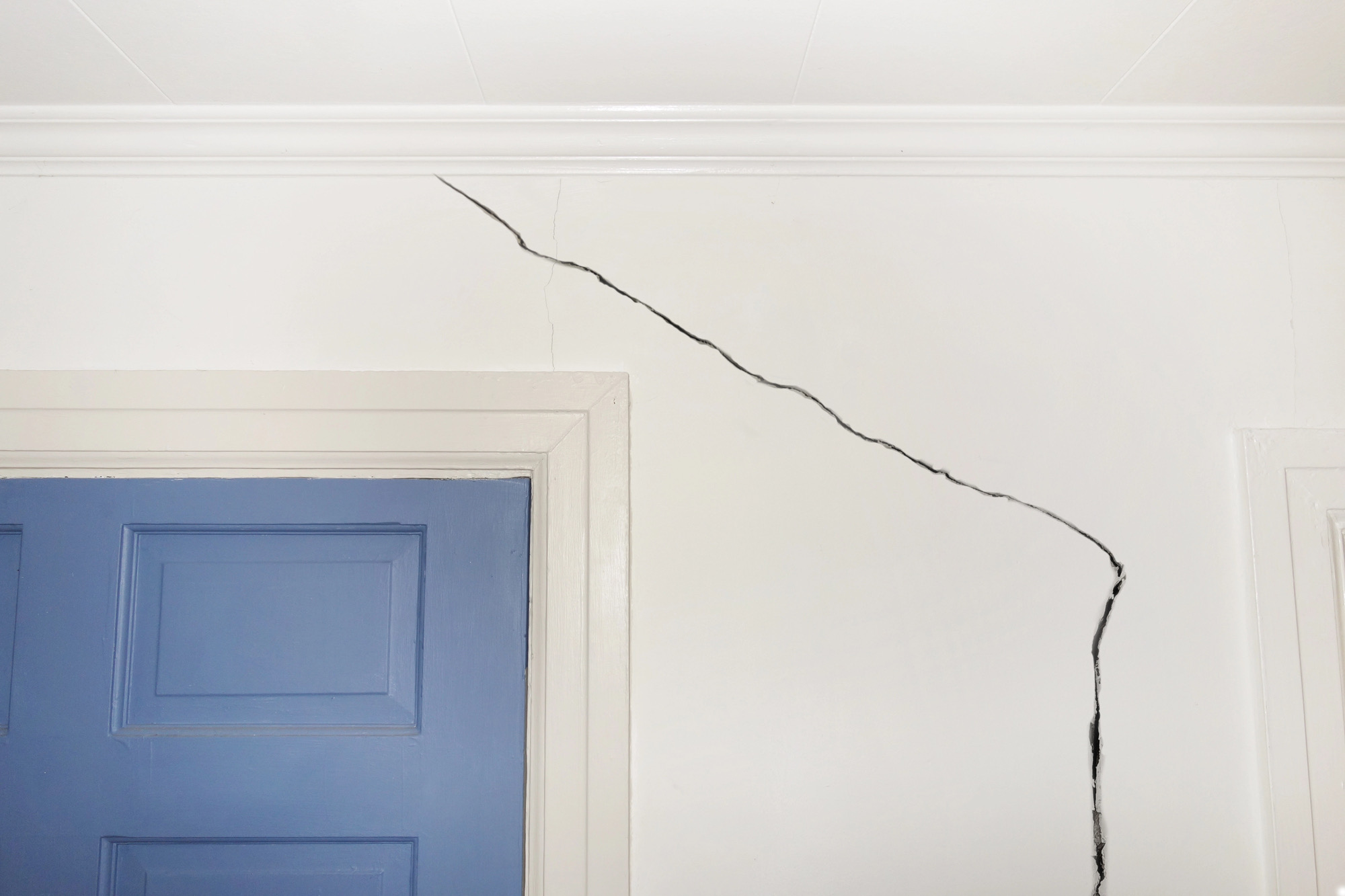 Diagonal drywall crack running up from the corner of a door frame