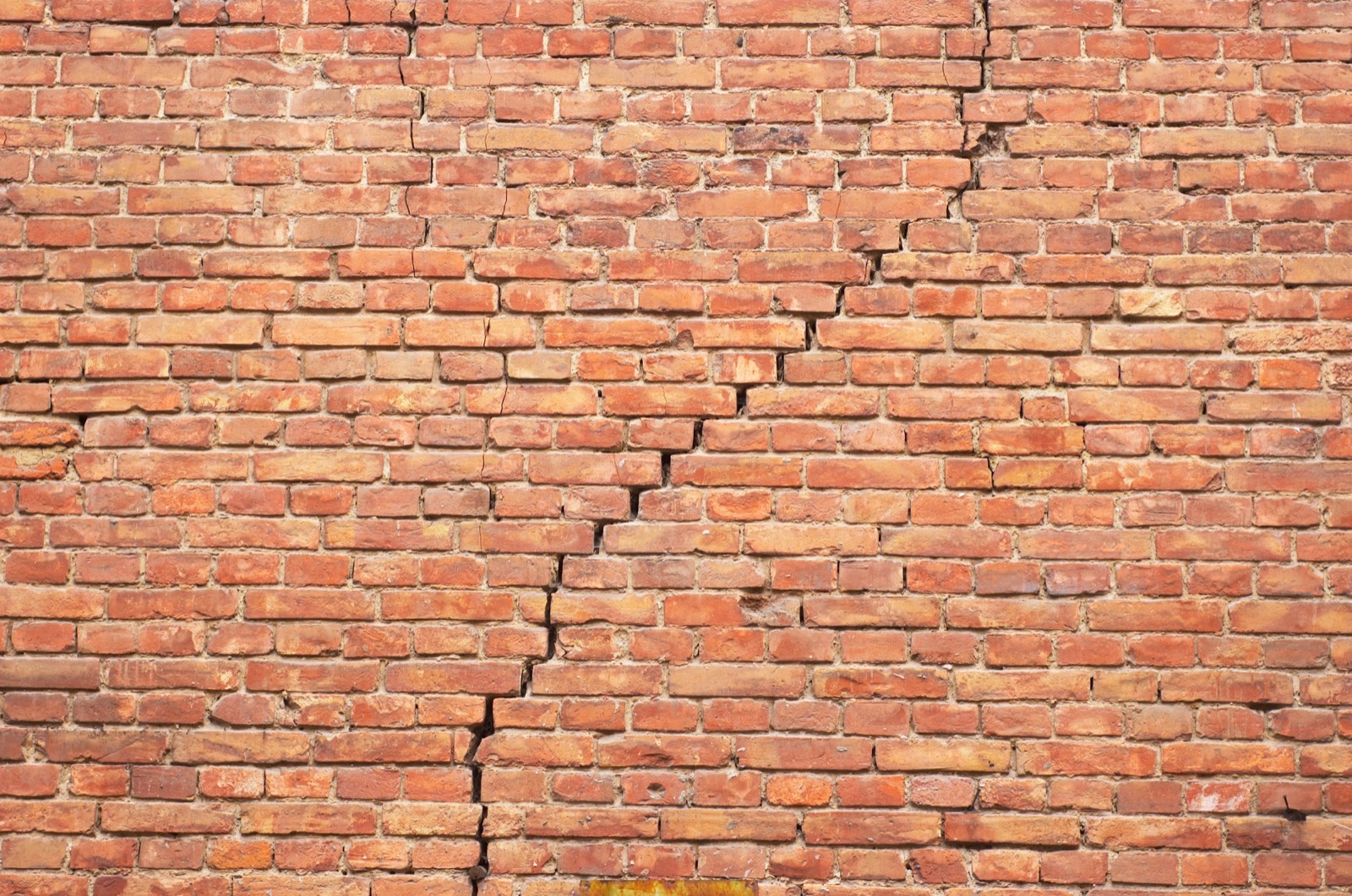 Stair-step crack running diagonally through the mortar joints of a brick wall