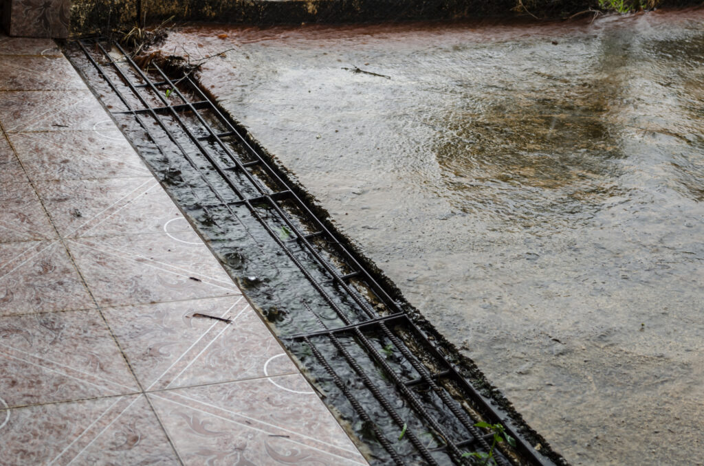 Water from the road runs down the concrete paved driveway